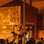 umbrella A fire illuminates protesters standing on a barricade in front of the Third Police Precinct in Minneapolis