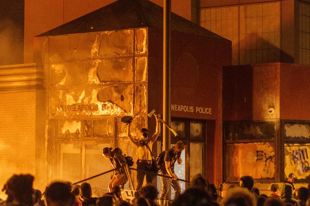 umbrella A fire illuminates protesters standing on a barricade in front of the Third Police Precinct in Minneapolis