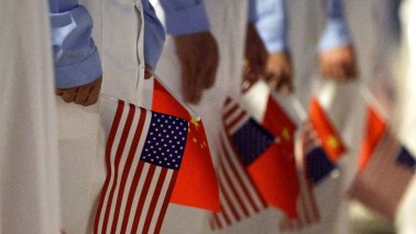 BEIJING, CHINA - MAY 13: Chinese youth hold American and Chinese flags as they join officials to welcome U.S. President Donald Trump at Beijing Capital International Airport on May 13, 2026 in Beijing, China. President Trump is meeting with President Xi Jinping in Beijing to address the Iran conflict, trade imbalances, and the Taiwan situation while establishing new bilateral boards for economic and AI oversight. (Photo by Alex Wong/Getty Images)