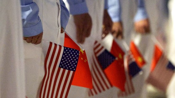 BEIJING, CHINA - MAY 13: Chinese youth hold American and Chinese flags as they join officials to welcome U.S. President Donald Trump at Beijing Capital International Airport on May 13, 2026 in Beijing, China. President Trump is meeting with President Xi Jinping in Beijing to address the Iran conflict, trade imbalances, and the Taiwan situation while establishing new bilateral boards for economic and AI oversight. (Photo by Alex Wong/Getty Images)